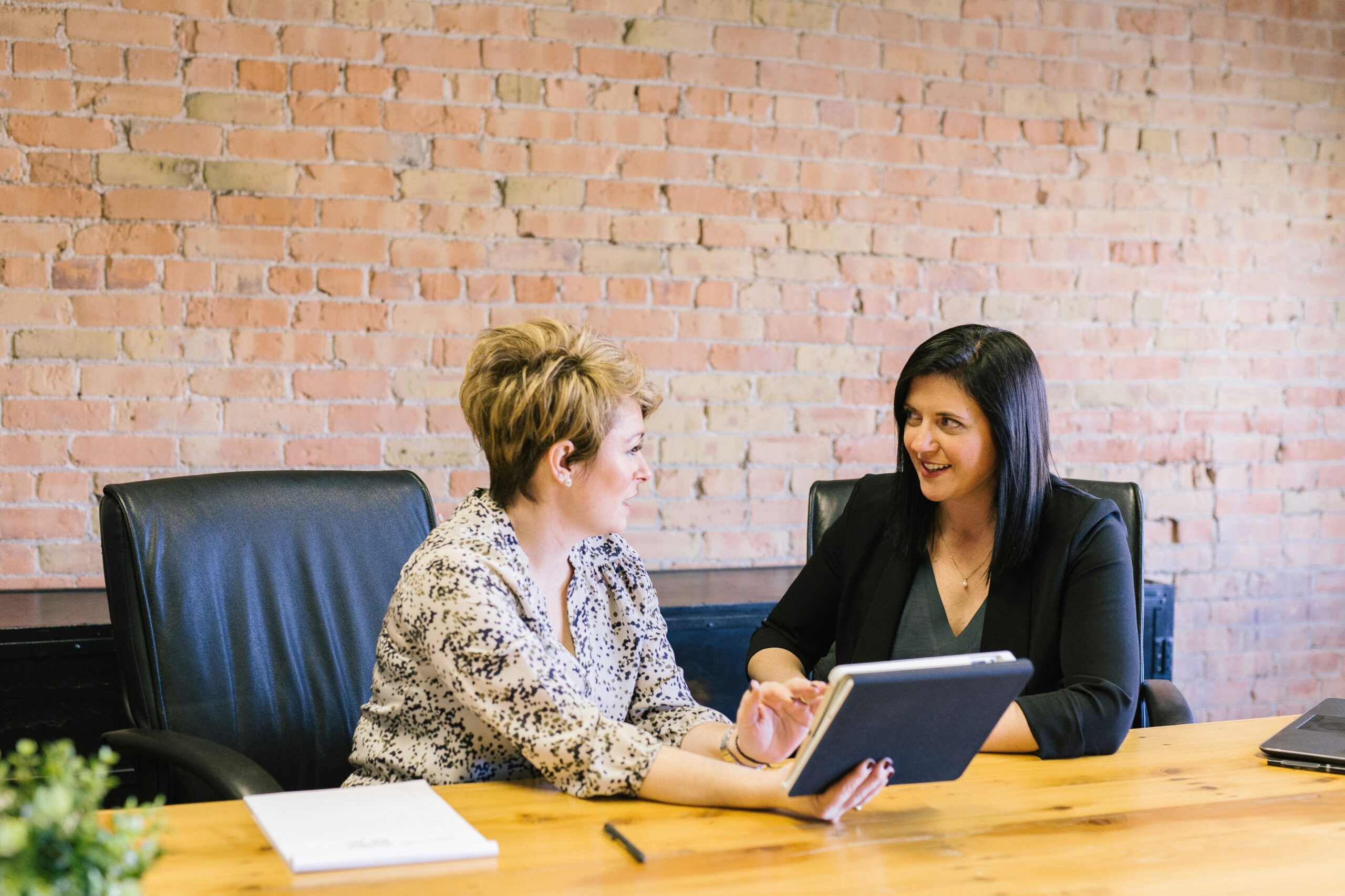Two women at a table discussing while looking at a laptop