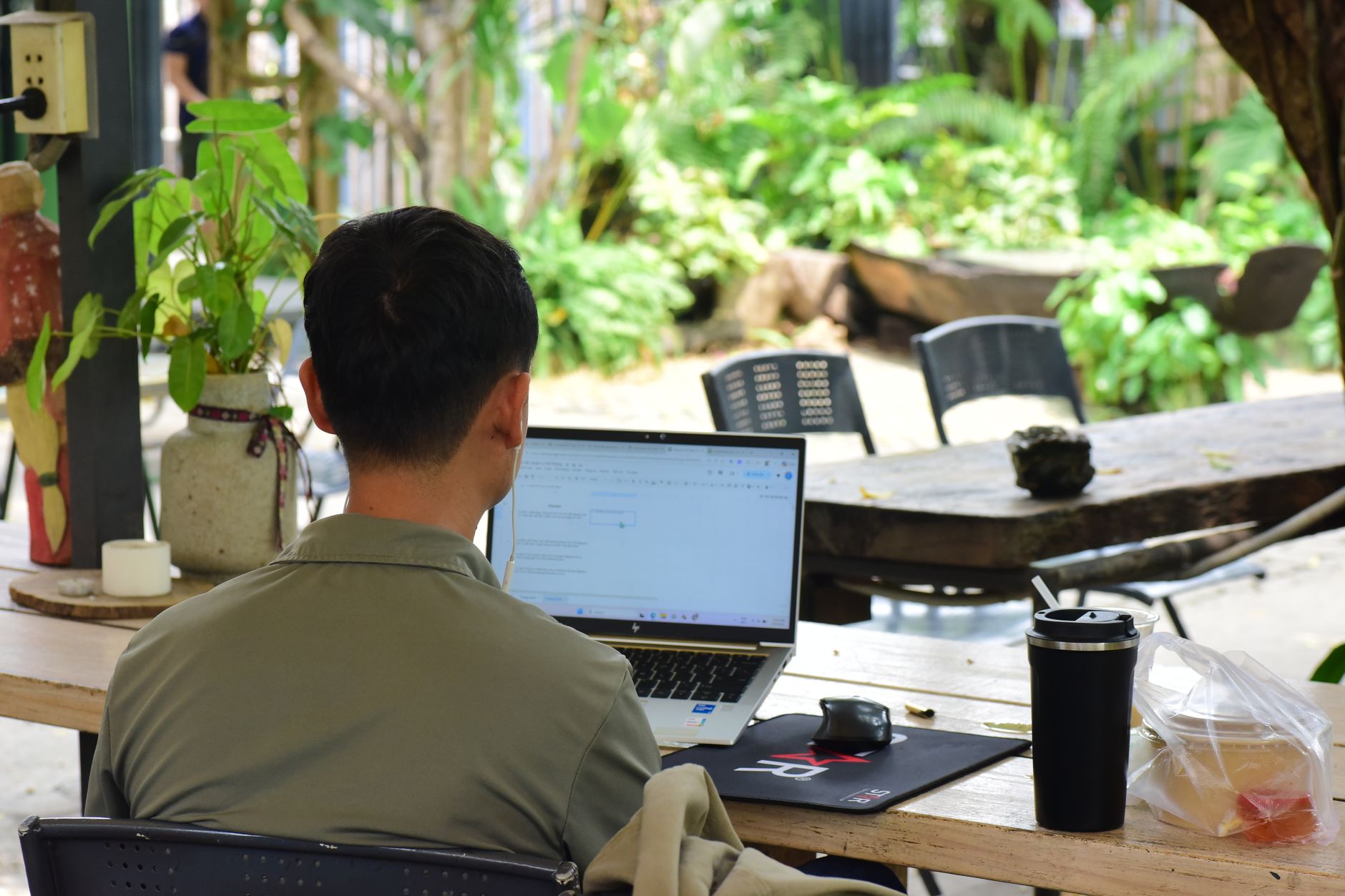 young man working on laptop outdoors in garden setting
